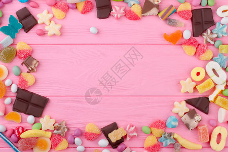 粉红色木质背景上的多彩甜品图片
