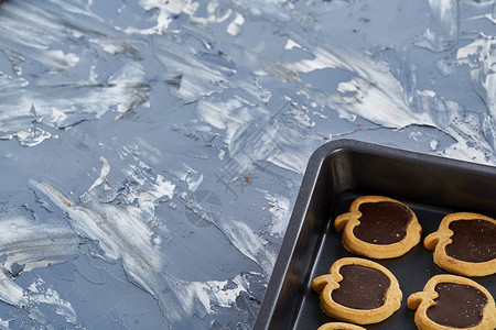 在抽象纹理光背景浅景深选择聚焦的金属饼干片上排列的即食美味苹果形巧克力饼干图片