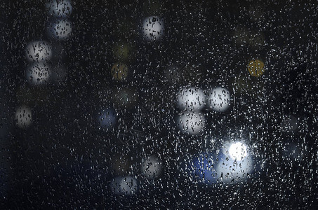 雨滴在夜景背下的窗户上带有散焦灯的情感忧郁抽象背景由于景深较浅图片