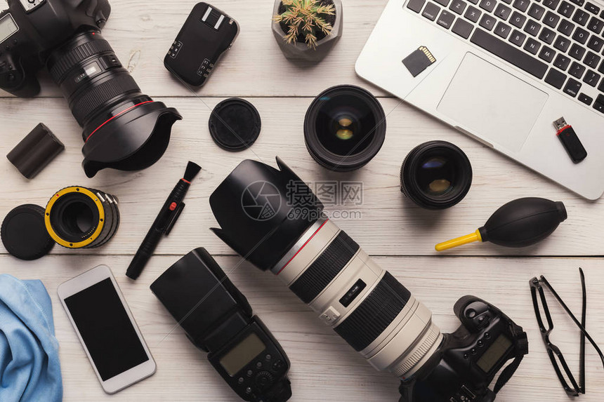 摄影师的各种个人设备和白色木桌上清洁和护理工具的顶部视图片
