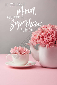 灰色背景的杯子和茶壶中的粉色康乃馨花图片
