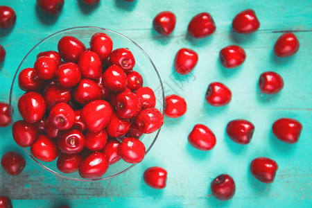 番茄鱼片碗里新鲜的红樱桃在旧漆木制桌子上作为季节卡片海报博客网络设计的明亮多插画