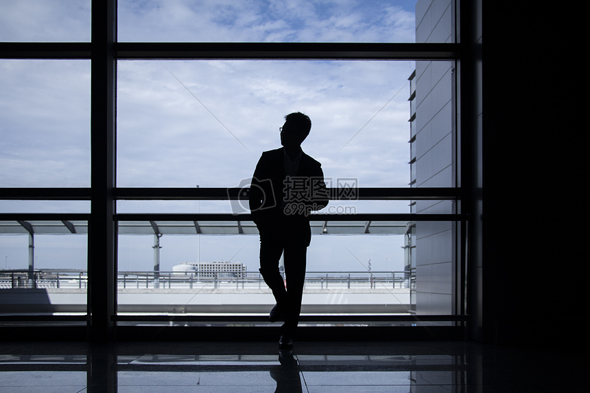 商务人士站在机场落地窗前