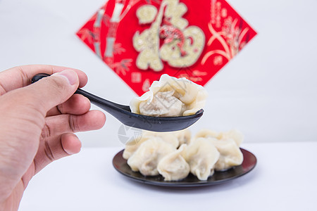 福字为背景的人夹饺子吃的冬至新春节日图片