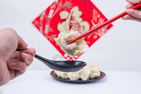 福字为背景的人夹饺子吃的冬至新春节日背景图片