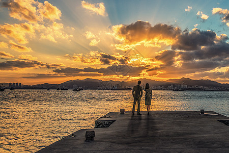 海边漫步夕阳下母子牵手漫步于海边背景