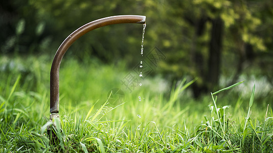 绿色出行草坪里的水龙头滴水瞬间设计图片