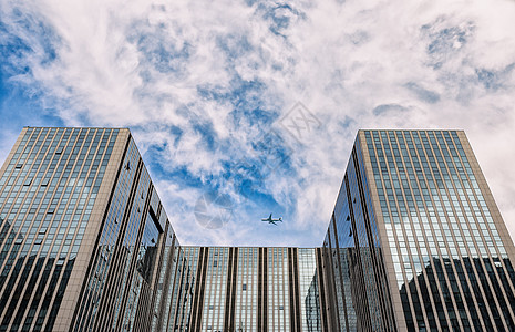 飞机划过建筑上空蓝天白云建筑和飞机背景