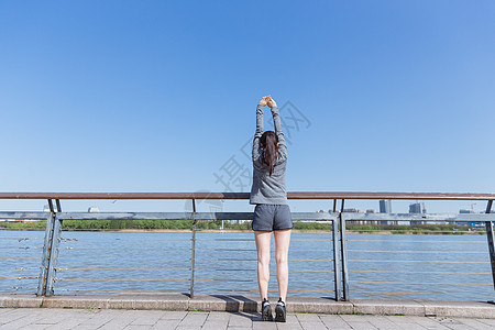 运动女孩阳光下拉伸身体高清图片