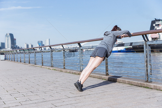 运动女孩阳光下扶栏杆压腿图片