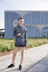 运动服落日运动女孩手拿球拍打羽毛球背景