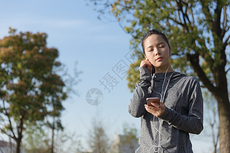 公园运动女孩阳光下休息听音乐图片