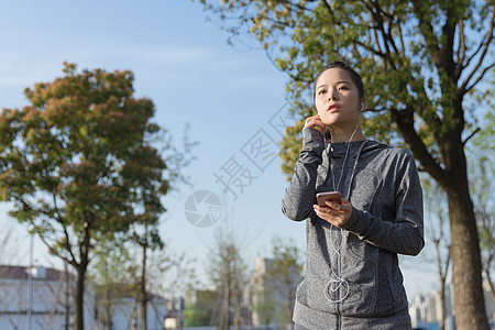 公园运动女孩阳光下休息听音乐图片