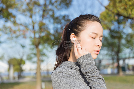 公园运动女孩阳光下休息听音乐图片