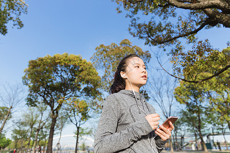 公园运动女孩阳光下休息听音乐图片