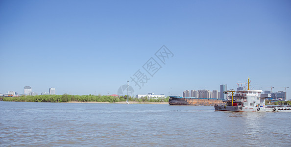 蓝天下的河面运输的船背景图片