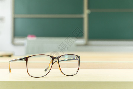 教室里书桌上的眼镜特写背景图片