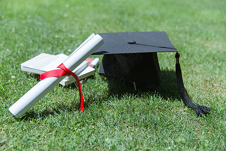 毕业季背景大学草地上的书本证书学士帽背景