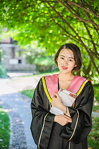毕业季穿学士服抱书的学生背景图片