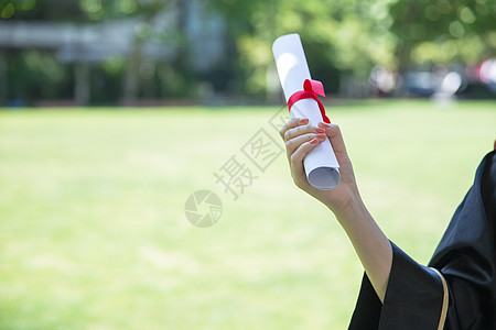 女孩手拿学士帽草地上手拿毕业证的毕业生背景