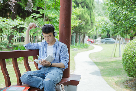 文艺男生看书帅气大学生坐在凉亭听音乐看书背景