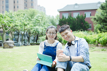 在阳光下的女性阳光下男女大学生在看平板电脑背景