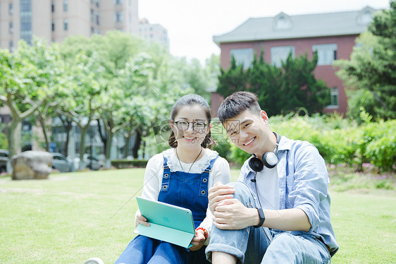 阳光下男女大学生在看平板电脑图片