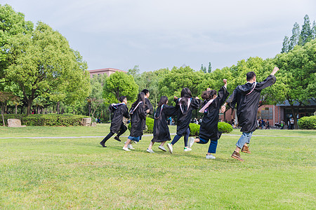 穿学士服的男孩毕业季穿学士服的学生在奔跑背景