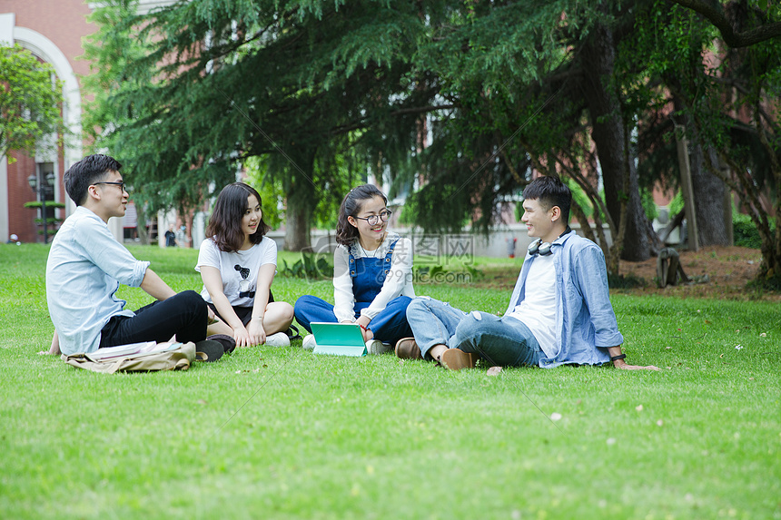 男女大学生们坐草地上聊天休息