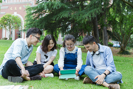 男女大学生们坐草地上聊天休息高清图片