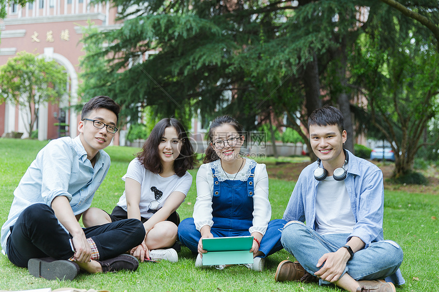 男女大学生们坐草地上聊天休息图片