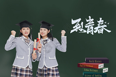 两个穿学士服的女孩在黑板前面留念背景图片