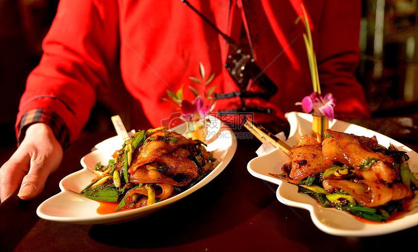 双手端着四川名菜回锅肉上菜