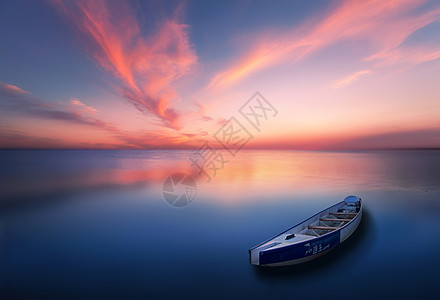 海日落一艘独木舟漂浮在平静的水面上背景