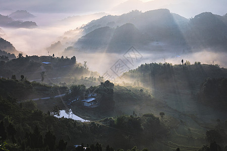 阳光穿透晨雾缭绕的山脉背景