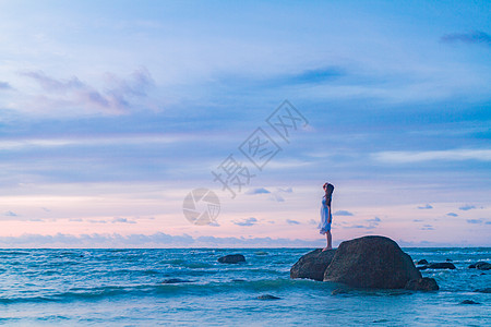 手绘海浪海边礁石上的少女背景