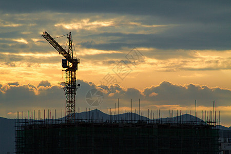 日出时的建筑工地塔吊背景图片