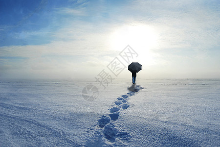 雪伞在雪上行走的人物背影设计图片