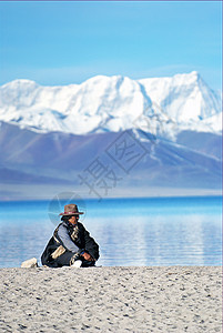 坐着的男人西藏纳木错雪山脚下的藏民背景