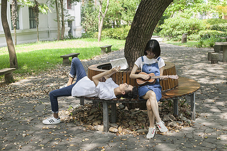 学校绿荫下男女同学在一起学音乐恋爱高清图片