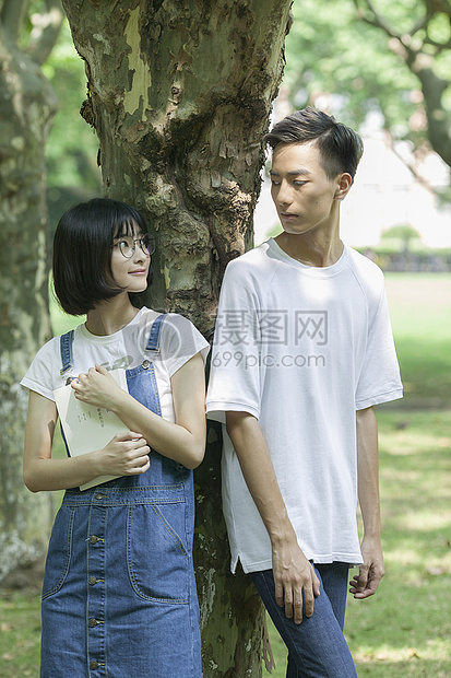 学校林荫道上男女同学下课一起学习看书