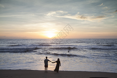 海边情侣情侣在夕阳西下的海边看大海背景