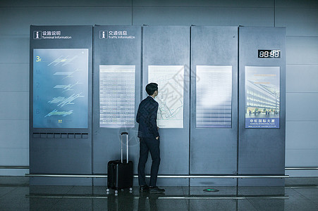商务男士手提拉杆箱在机场时刻表上看时间背景图片