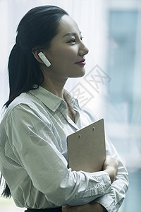 办公室上班办公室里商务女士使用蓝牙耳机接听工作电话背景