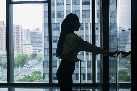 商务楼里商务女士手提拉杆箱等电梯图片