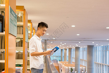 站在图书馆书架旁看书的帅气男同学图片