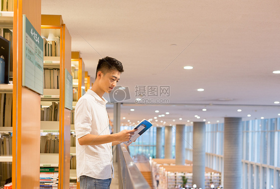 站在图书馆书架旁看书的帅气男同学图片