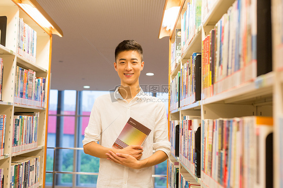 站在图书馆书架旁看书的帅气男同学图片