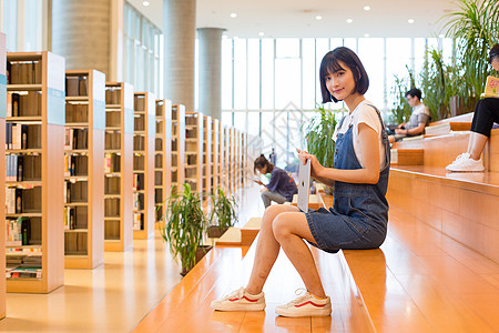 看书的女生坐在图书馆使用平板的女生背景