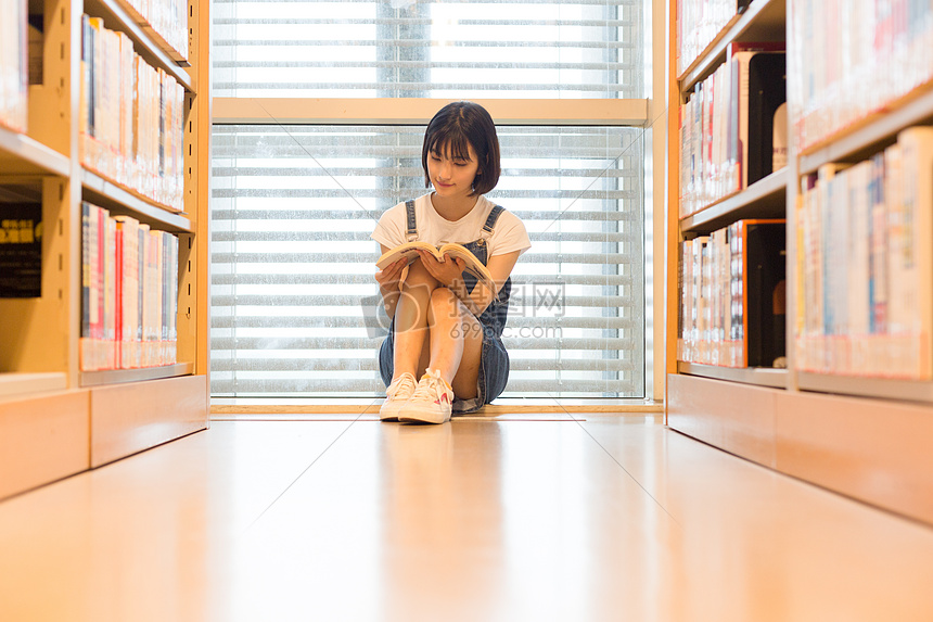 坐在图书馆书架旁看书的可爱女生图片